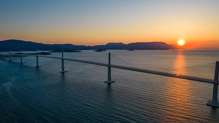See the sun set over the Pelješac bridge, Croatia
