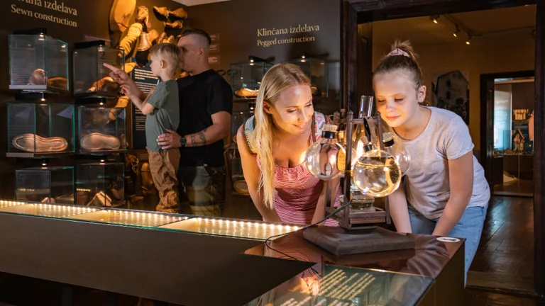 Visitors explore a museum exhibit featuring historical artifacts and glass displays, with a focus on an intriguing laboratory instrument.