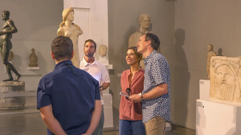 Visitors admire a variety of ancient sculptures in a modern museum setting, showcasing artistic masterpieces and historical artifacts.