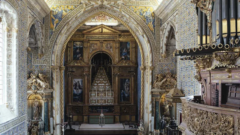 Intricate chapel interior featuring ornate arches, a richly decorated altar, vibrant tiles, and a grand organ against a backdrop of history.