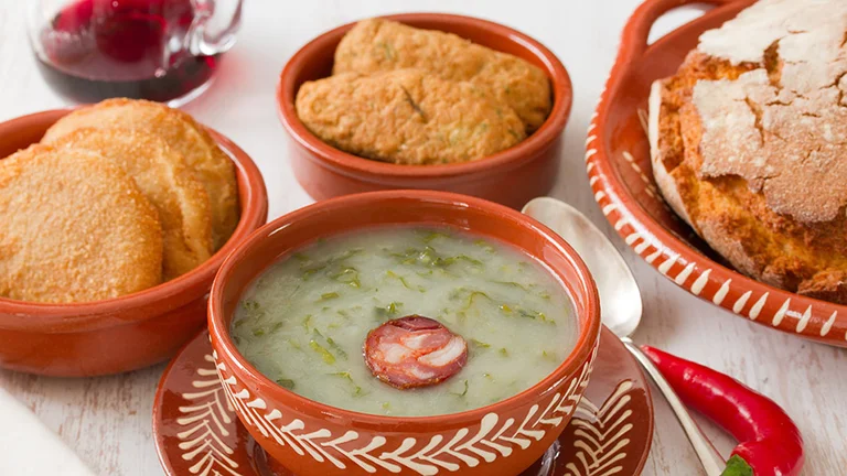 Traditional Portuguese Caldo Verde soup with chorizo, cornbread and fried snacks.
