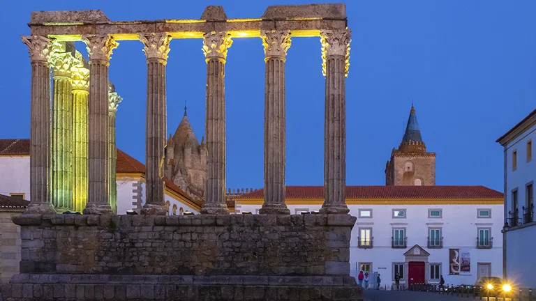 Ruins of the Roman Temple in Évora, Portugal, with Corinthian columns rising against a bright blue sky in the historic Alentejo city.