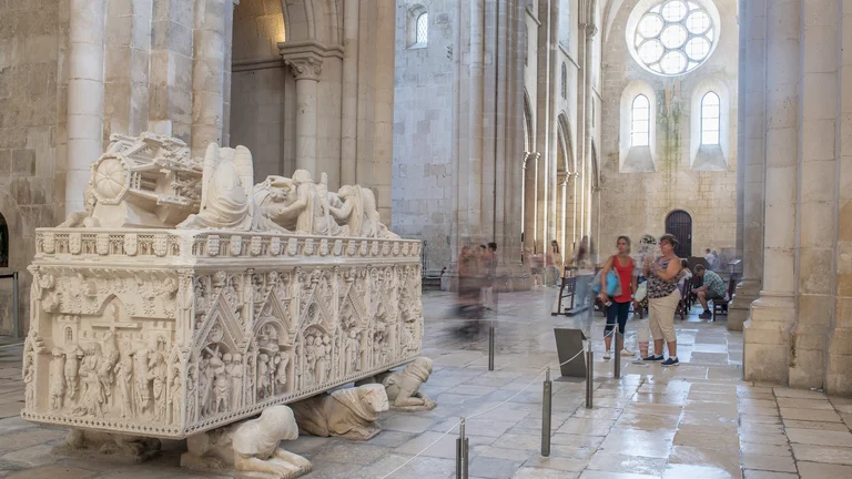 Ornate medieval tomb inside vast stone abbey.