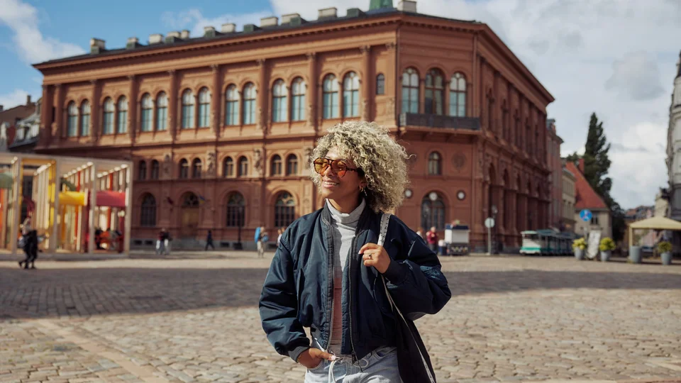 Traveler walking across a historic Dome square in Riga’s Old Town, surrounded by heritage buildings.