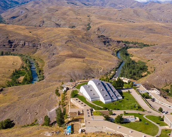 Aerial view of the İstanbul Archaeological Museums nestled in a dry mountainous landscape with a winding river.