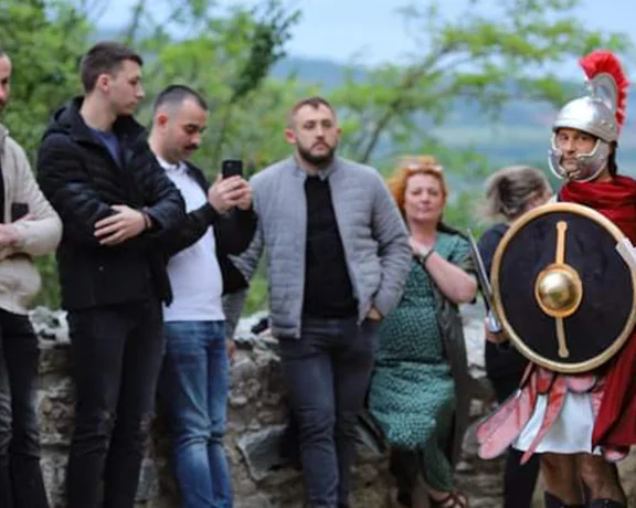 Group of people standing with a person in historical Roman costume holding a shield.