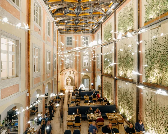 Elegant indoor courtyard dining with hanging lights and greenery on walls.