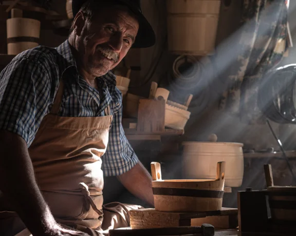 A skilled craftsman works intently on a wooden bowl amidst a warmly lit workshop filled with various handcrafted items.