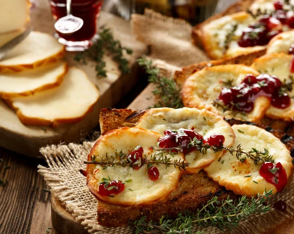 A plate with traditional Polish cheese topped with cranberries, served alongside slices of bread.