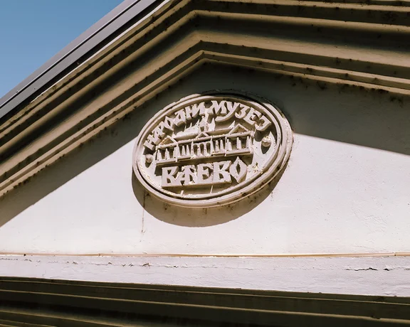 Stone emblem of the National Museum of Valjevo in Serbia, showcasing traditional architectural relief details under bright sunlight.