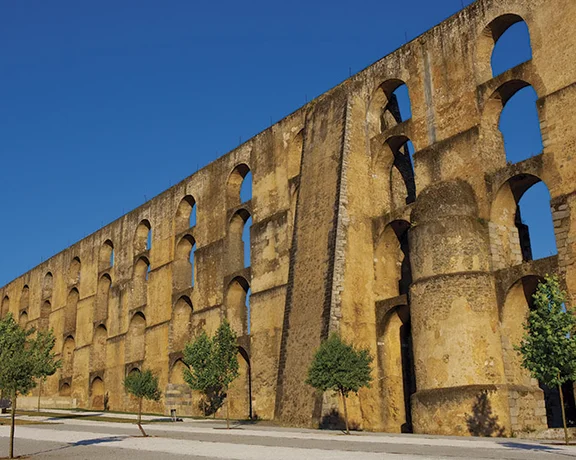 Elvas Aqueduct stretching across the landscape under a clear blue sky, showcasing its tall stone arches.