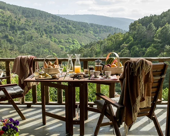 Schist houses of Cerdeira Village (Aldeias do Xisto) nestled on a hillside, surrounded by lush green forest in the Serra da Lousã, Portugal.
