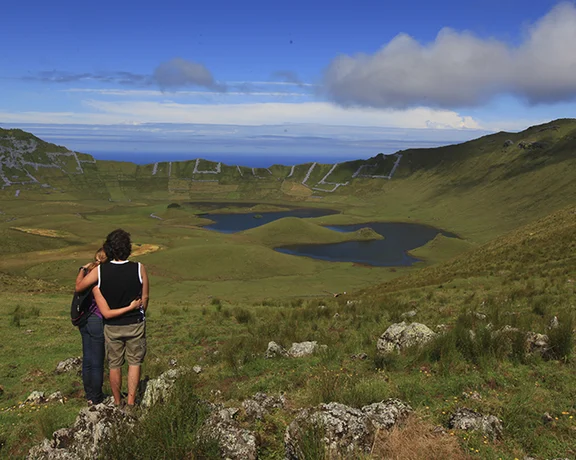 Crater of the Caldeirão volcano on Corvo Island, Azores, showing a deep circular caldera with green slopes and a lake at the bottom.