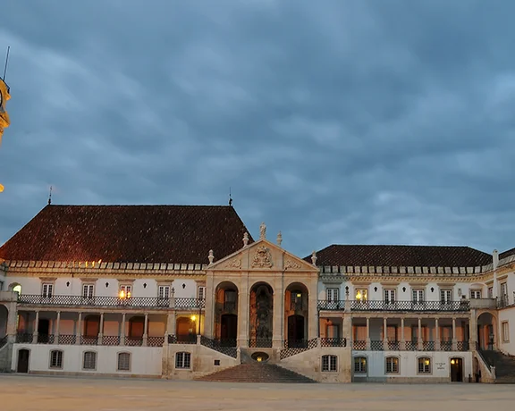 Pátio das Escolas at the University of Coimbra, softly illuminated at night, showing historic stone buildings and a serene courtyard under the stars.