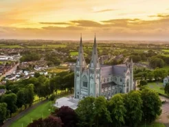 Aerial view of St. Patrick's Cathedral at sunset, surrounded by lush greenery and a small town in the foreground.